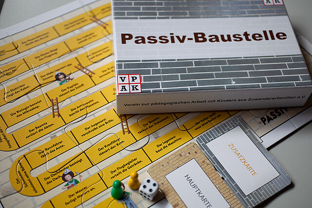 Puzzleteilchen mit gelben Hintergrund, Kartonverpackung und Spielfiguren/Karten