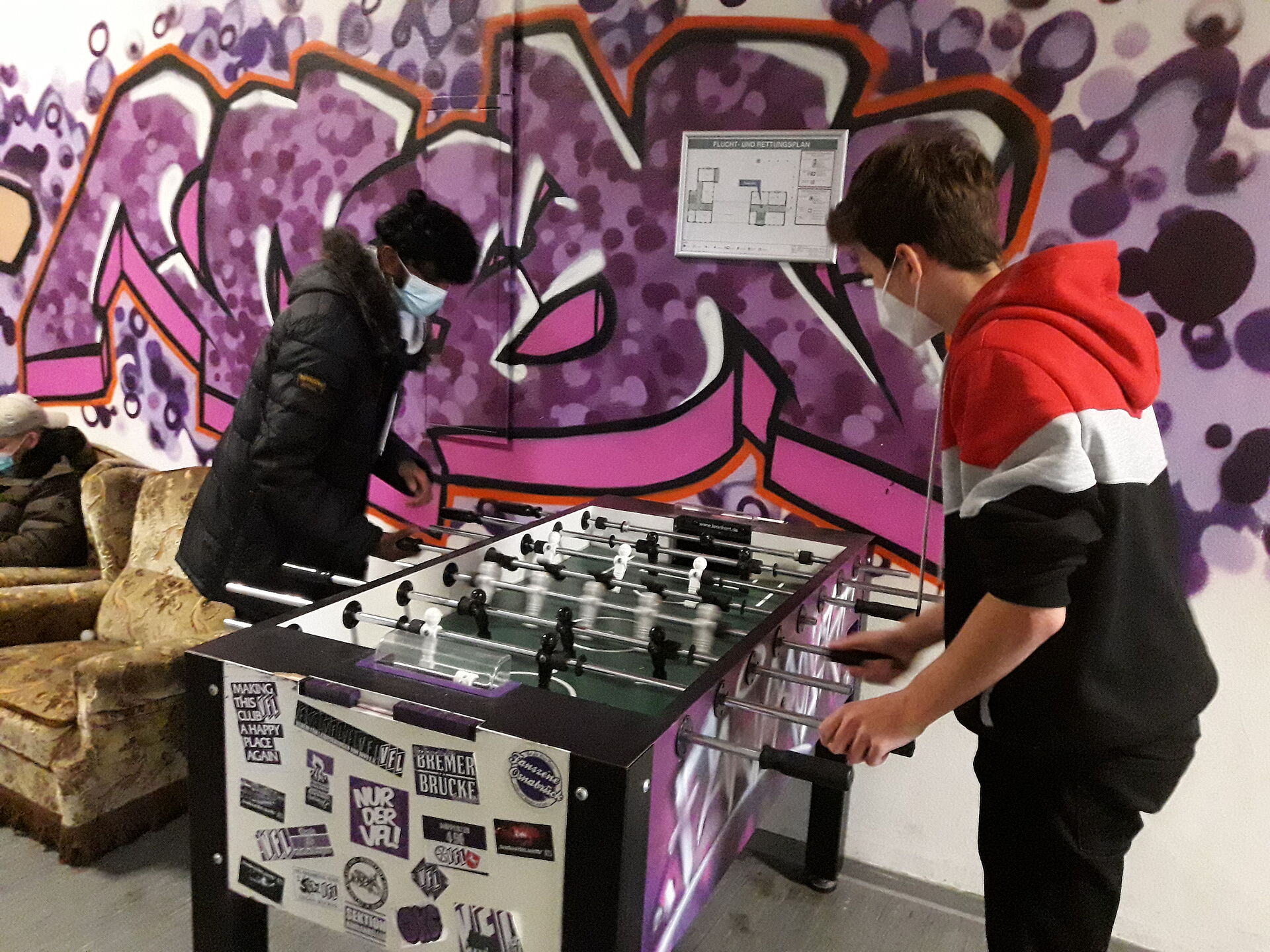 Zwei Jugendliche spielen Kicker. 